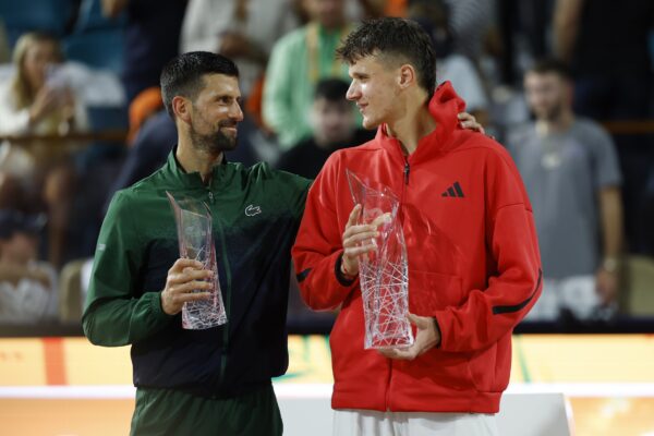 Mar 30, 2025; Miami, FL, USA; (L-R) Novak Djokovic (SRB) hugs Jakub Mensik (CZE) while holding the finalist and Butch Buchholz championship trophies, respectively, after their men's singles championship of the Miami Open at Hard Rock Stadium.