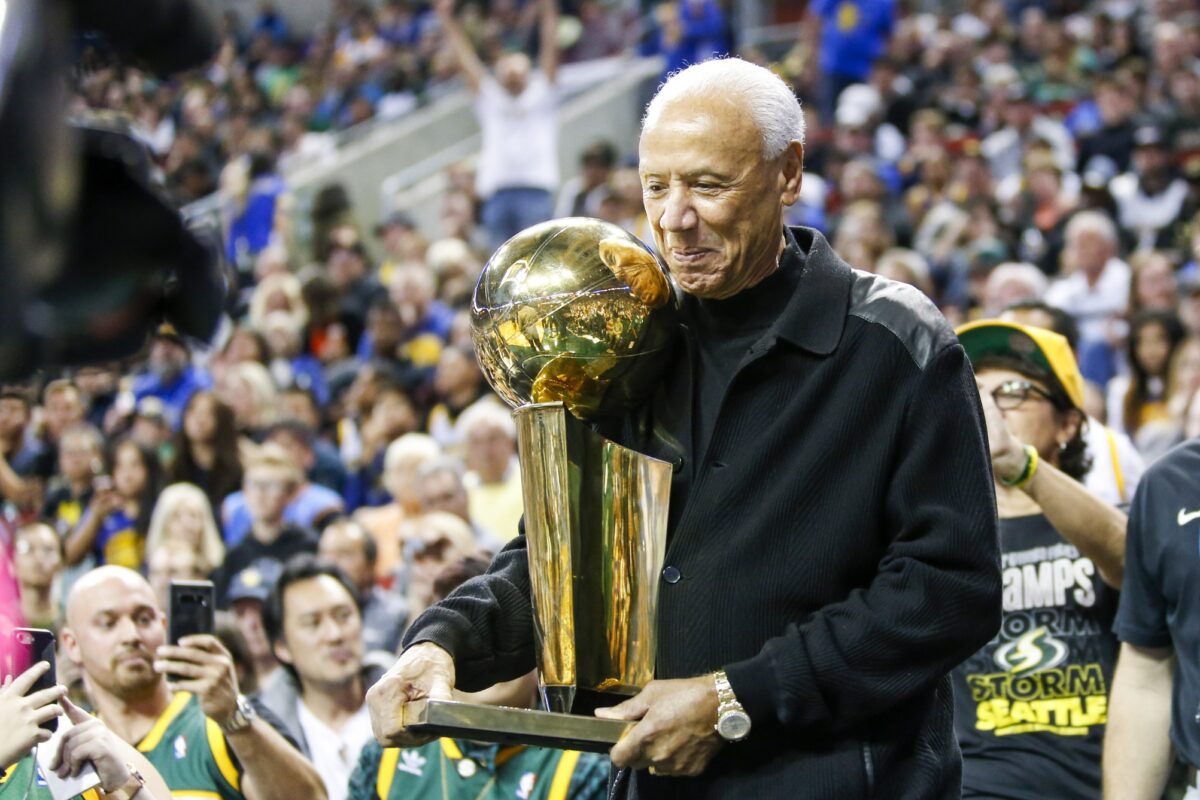 Former Seattle Supersonics head coach Lenny Wilkens holds the 1979 championship trophy during a third quarter timeout of a game between the Sacramento Kings and Golden State Warriors at KeyArena.
