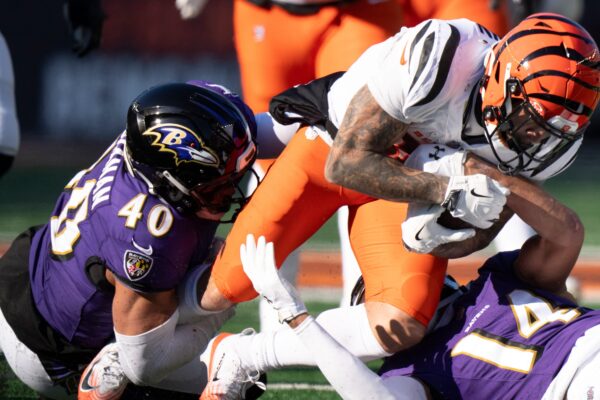 Baltimore Ravens safety Kyle Hamilton (14) and Baltimore Ravens inside linebacker Teddye Buchanan (40) tackle Cincinnati Bengals running back Chase Brown (30) in the first quarter of the NFL football game at Paycor Stadium in Cincinnati on Dec. 14, 2025.