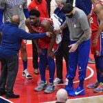 Mar 12, 2021; Washington, District of Columbia, USA; Philadelphia 76ers center Joel Embiid (middle) is examined by a trainer after suffering an apparent leg injury against the Washington Wizards during the third quarter at Capital One Arena. Mandatory Credit: Brad Mills-USA TODAY Sports