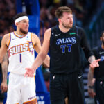 Feb 22, 2024; Dallas, Texas, USA; NBA; Dallas Mavericks guard Luka Doncic (77) reacts in front of Phoenix Suns guard Devin Booker (1) during the first half at American Airlines Center.