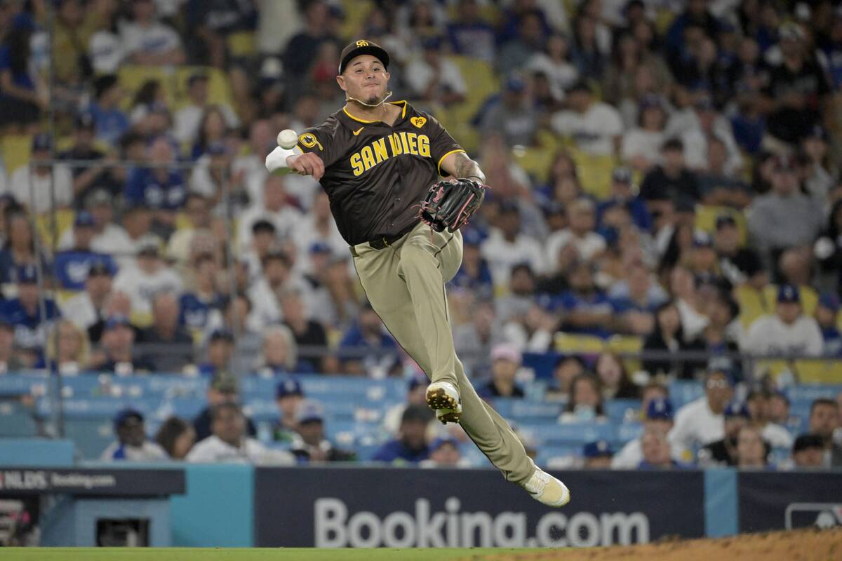 Oct 6, 2024; Los Angeles, California, USA; San Diego Padres third baseman Manny Machado (13) attempts to throw to first against Los Angeles Dodgers outfielder Tommy Edman (25) in the eighth inning during game two of the NLDS for the 2024 MLB Playoffs at Dodger Stadium. Mandatory Credit: Jayne Kamin-Oncea-Imagn Images