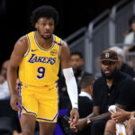 PALM SPRINGS, CALIFORNIA - OCTOBER 04: LeBron James #23 watches the game from the bench as Bronny James #9 of the Los Angeles Lakers looks on during the second half of a game against the Minnesota Timberwolves at Acrisure Arena on October 04, 2024 in Palm Springs, California.