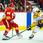 Calgary Flames left wing Andrei Kuzmenko (96) and Nashville Predators center Philip Tomasino (26) battles for the puck during the second period at Scotiabank Saddledome.