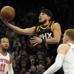 Dec 15, 2023; NBA; Phoenix, Arizona, USA; Phoenix Suns guard Devin Booker (1) drives between New York Knicks guard Jalen Brunson (11) and guard Donte DiVincenzo (0) in the first half at Footprint Center.