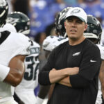 Aug 9, 2024; Baltimore, Maryland, USA; Philadelphia Eagles offensive coordinator Kellen Moore looks on as quarterback Jalen Hurts (1) throws before a preseason game against the Baltimore Ravens at M&T Bank Stadium. Mandatory Credit: Tommy Gilligan-USA TODAY Sports