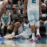 Nov 6, 2024; Charlotte, North Carolina, USA; Charlotte Hornets forward Miles Bridges (0) holds his knee after a collision at the basket against the Detroit Pistons during the second half at Spectrum Center. Mandatory Credit: Jim Dedmon-Imagn Images