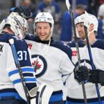 Winnipeg Jets goalie Connor Hellebuyck (37) and defenseman Colin Miller (6) and forward David Gustafsson (19) celebrate a win over the Toronto Maple Leafs at Scotiabank Arena.
