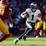Dec 22, 2024; Landover, Maryland, USA; Philadelphia Eagles quarterback Jalen Hurts (1) against Washington Commanders safety Jeremy Chinn (11) during the first quarter at Northwest Stadium. Mandatory Credit: Peter Casey-Imagn Images