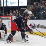 Montreal Canadiens center Kirby Dach (77) grabs a loose puck as Columbus Blue Jackets defenseman Zach Werenski (8) defends during the first period at Nationwide Arena.