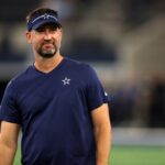 Aug 26, 2023; Arlington, Texas, USA; Dallas Cowboys offensive coordinator Brian Schottenheimer on the field before the game against the Las Vegas Raiders at AT&T Stadium.