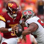 Sep 8, 2024; Tampa, Florida, USA; Washington Commanders quarterback Jayden Daniels (5) os pressured by Tampa Bay Buccaneers defensive tackle Vita Vea (50) in the third quarter at Raymond James Stadium.