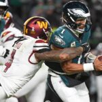 Nov 14, 2024; Philadelphia, Pennsylvania, USA; Philadelphia Eagles quarterback Jalen Hurts (1) is sacked by Washington Commanders linebacker Frankie Luvu (4) during the first quarter at Lincoln Financial Field. Mandatory Credit: Eric Hartline-Imagn Images