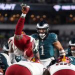 Jan 26, 2025; Philadelphia, PA, USA; Philadelphia Eagles quarterback Jalen Hurts (1) reacts as Washington Commanders linebacker Frankie Luvu (4) leaps over linemen before a snap during the second half in the NFC Championship game at Lincoln Financial Field. Mandatory Credit: Bill Streicher-Imagn Images