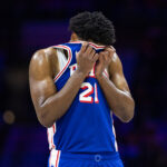 Feb 20, 2025; Philadelphia, Pennsylvania, USA; Philadelphia 76ers center Joel Embiid (21) wipes his face during a break in the third quarter against the Boston Celtics at Wells Fargo Center.