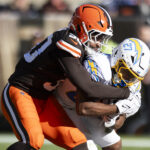 Nov 3, 2024; Cleveland, Ohio, USA; Los Angeles Chargers running back J.K. Dobbins (27) runs the ball as Cleveland Browns linebacker Devin Bush (30) tackles him during the second quarter at Huntington Bank Field. Mandatory Credit: Scott Galvin-Imagn Images
