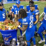 Onde Assistir NFL Semana 13 - Nov 28, 2024; Detroit, Michigan, USA; Detroit Lions quarterback Jared Goff (16) passes out pieces of the John Madden MVP Turkey to teammates after the annual Thanksgiving Day game defeating the Chicago Bears at Ford Field. Mandatory Credit: David Reginek-Imagn Images