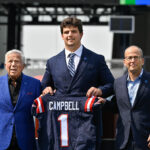 Apr 25, 2025; Foxborough, MA, USA; New England Patriots first round draft pick Will Campbell is presented with a ceremonial first round jersey by team owner Robert Kraft (l) and team president Jonathan Kraft (r) at a press conference on the game field at Gillette Stadium. Mandatory Credit: Eric Canha-Imagn Images