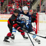 Mar 9, 2025; Raleigh, North Carolina, USA; Carolina Hurricanes defenseman Shayne Gostisbehere (4) and Winnipeg Jets left wing Nikolaj Ehlers (27) battle over the puck during the second period at Lenovo Center. Mandatory Credit: James Guillory-Imagn Images