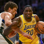 Mar 20, 2025; Los Angeles, California, USA; Los Angeles Lakers guard Shake Milton (20) charges the basket against Milwaukee Bucks center Brook Lopez (11) during the second half at Crypto.com Arena.