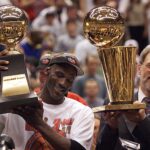 Michael Jordan holds the MVP trophy and coach Phil Jackson holds the championship trophy after the Bulls beat the Jazz to win their sixth title in 1998.