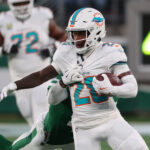 Jan 5, 2025; East Rutherford, New Jersey, USA; Miami Dolphins running back De'Von Achane (28) runs with the ball while New York Jets cornerback D.J. Reed (4) attempts to tackle him during the first quarter at MetLife Stadium. Mandatory Credit: Ed Mulholland-Imagn Images