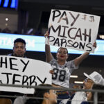 Aug 16, 2025; Arlington, Texas, USA; Dallas Cowboys fans hold up signs to owner Jerry Jones and defensive end Micah Parsons (11) during the second half of the game against the Baltimore Ravens at AT&T Stadium. Mandatory Credit: Jerome Miron-Imagn Images