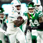 Miami Dolphins running back De'Von Achane (28) scores a touchdown after running past New York Jets cornerback Brandin Echols (26) and New York Jets linebacker Jamien Sherwood (44) in the fourth quarter, Sunday January 5, 2025, in East Rutherford.