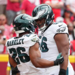 Sep 14, 2025; Kansas City, Missouri, USA; Philadelphia Eagles running back Saquon Barkley (26) celebrates after scoring a touchdown against the Kansas City Chiefs with guard Tyler Steen (56) during the first quarter of the game at GEHA Field at Arrowhead Stadium. Mandatory Credit: Denny Medley-Imagn Images