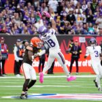 Oct 5, 2025; Tottenham, United Kingdom; Minnesota Vikings wide receiver Justin Jefferson (18) makes a catch against Cleveland Browns safety Rayshawn Jenkins (5) during the fourth quarter of an NFL International Series game at Tottenham Hotspur Stadium. Mandatory Credit: Kirby Lee-Imagn Images