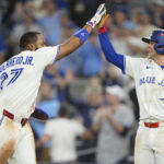 Oct 19, 2025; Toronto, Ontario, CAN; Toronto Blue Jays first baseman Vladimir Guerrero Jr. (27) celebrates after scoring on a throwing error with third baseman Ernie Clement (22) in the seven thinning against the Seattle Mariners during game six of the ALCS round for the 2025 MLB playoffs at Rogers Centre. Mandatory Credit: John E. Sokolowski-Imagn Images