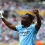 Atacante Jeremy Doku em campo pelo Manchester City, agradecendo ao céu
