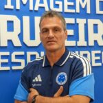 Executivo de futebol Bruno Spindel com a camisa do Cruzeiro, com um fundo azul atrás com os dizeres "a imagem do Cruzeiro resplandece" em letra bastão