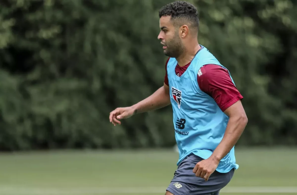 Alisson em treino do São Paulo, de colete azul e camisa grená por baixo