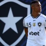 Danilo, de uniforme branco, antes de jogo do Botafogo com o escudo do clube atrás dele