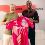 O goleiro Andrew Ventura (direita) segurando a camisa do Flamengo (rosa) ao lado do diretor de futebol José Boto (esquerda) em sala do Flamengo
