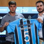 Juan Nardoni (esquerda) e o diretor de futebol Rafael Lima (direita) segurando a camisa 5 de Nardoni, novo reforço do Grêmio - sala de imprensa da Arena do Grêmio, sexta-feira (13/02/2026)