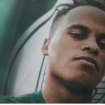 Jhon Arias com a camisa do Palmeiras no foto oficial da contratação do jogador por parte do clube paulista - escudo da equipe no canto superior esquerdo