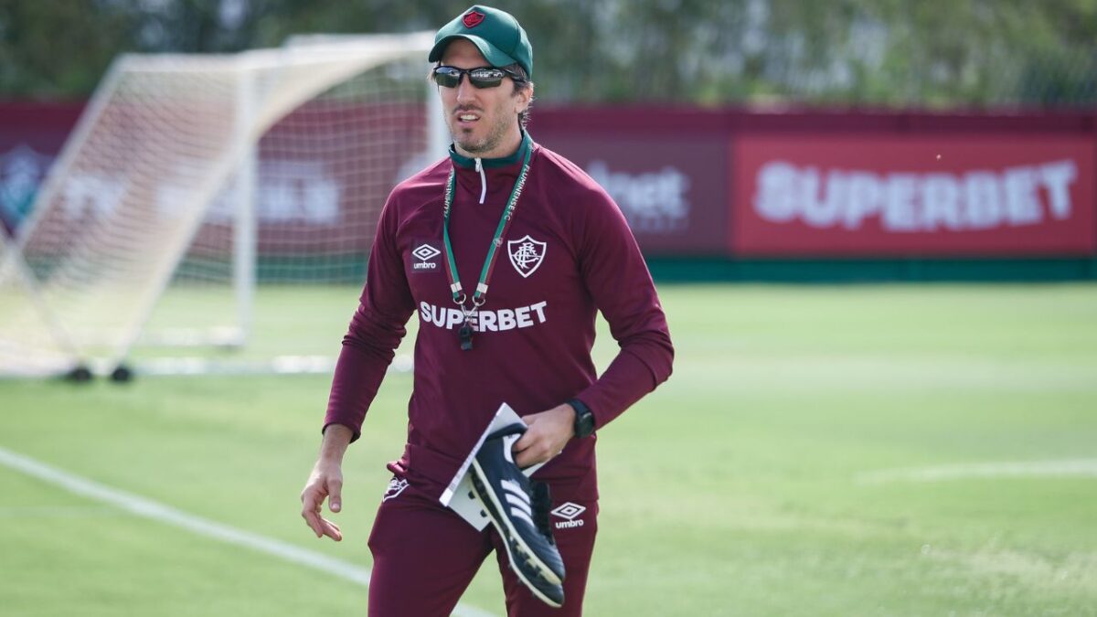 Técnico Luis Zubeldía no CT do Fluminense de óculos escuros, com apito em cordinha no pescoço e chuteira preta na mão esquerda
